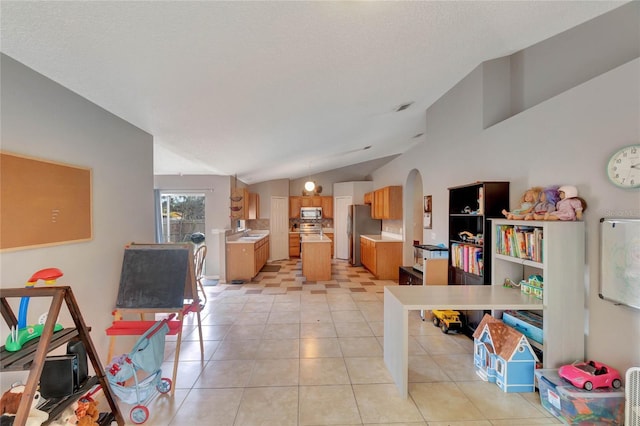 interior space with arched walkways, lofted ceiling, light tile patterned flooring, light countertops, and appliances with stainless steel finishes