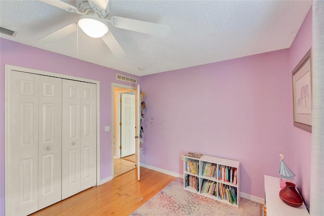 playroom featuring a textured ceiling, wood finished floors, visible vents, and baseboards