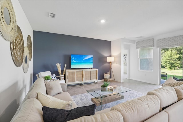 living area featuring visible vents, baseboards, an accent wall, tile patterned flooring, and recessed lighting