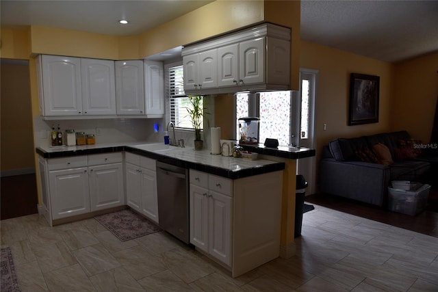 kitchen featuring white cabinetry, a sink, tile counters, stainless steel dishwasher, and open floor plan