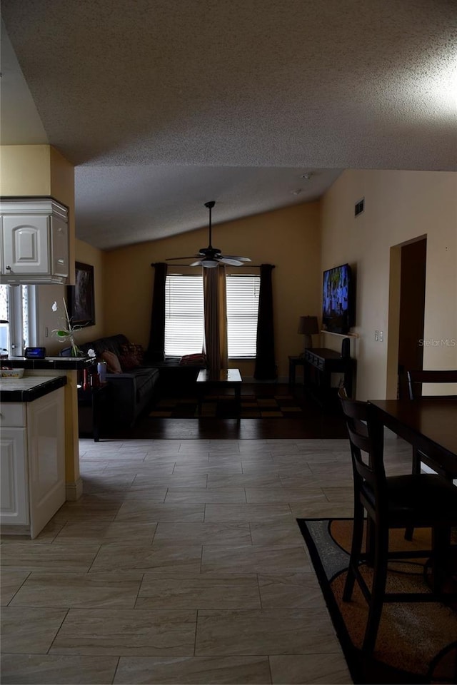 dining room with visible vents, a textured ceiling, a ceiling fan, and lofted ceiling