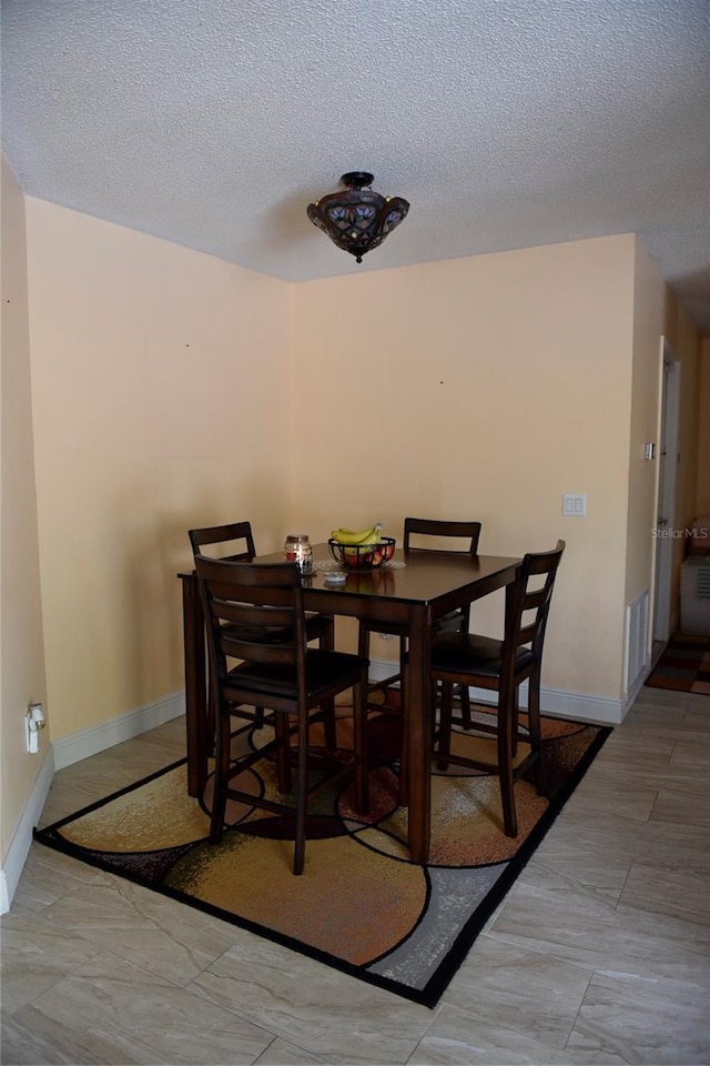 dining room featuring visible vents, a textured ceiling, and baseboards