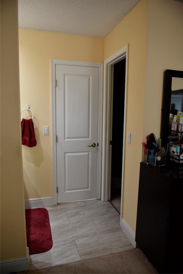 hallway featuring baseboards and a textured ceiling