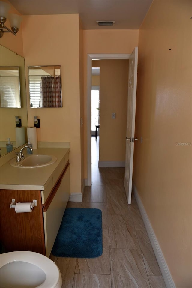 bathroom with a wealth of natural light, toilet, vanity, and baseboards