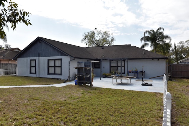 rear view of house featuring a patio, a lawn, and fence