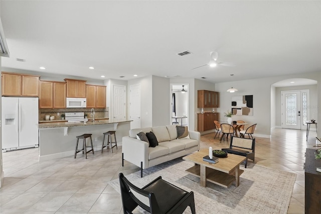 living room featuring arched walkways, visible vents, recessed lighting, and light tile patterned floors