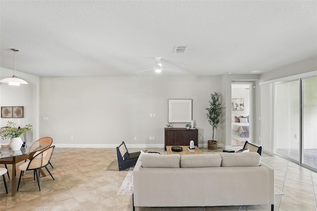 living room with visible vents, a textured ceiling, baseboards, and light tile patterned floors