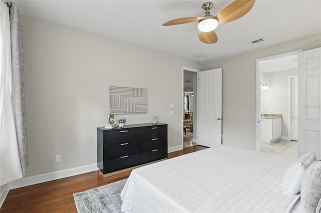 bedroom featuring ensuite bath, baseboards, visible vents, and wood finished floors