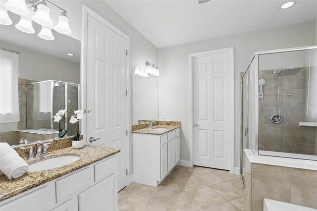 bathroom with a stall shower, tile patterned flooring, two vanities, and a sink