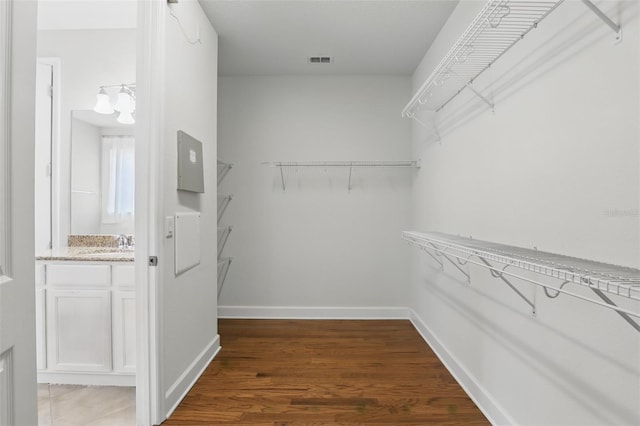 walk in closet featuring visible vents, a sink, and wood finished floors