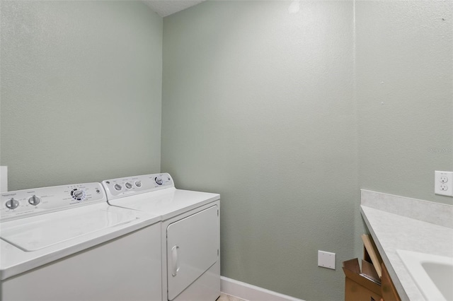 clothes washing area with baseboards, laundry area, and washer and dryer