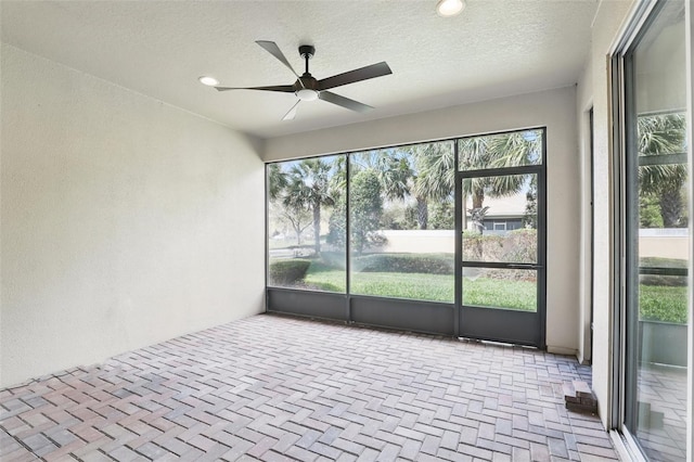 unfurnished sunroom featuring a ceiling fan