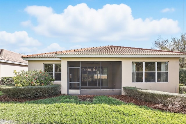 rear view of house with a sunroom, stucco siding, and a yard