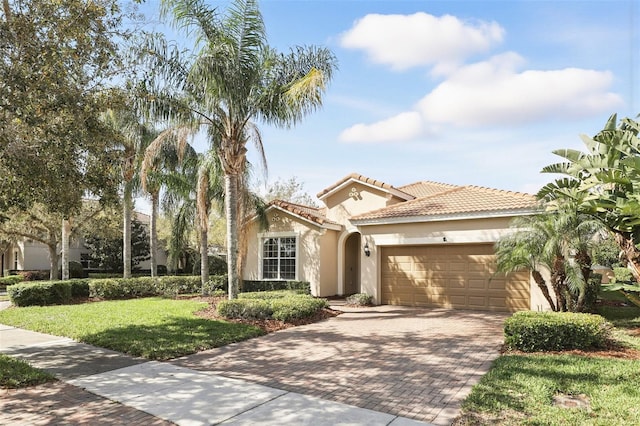 mediterranean / spanish-style house with stucco siding, a tiled roof, an attached garage, decorative driveway, and a front yard