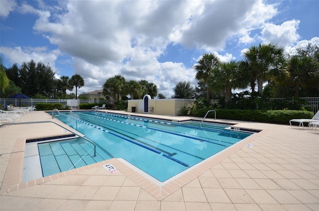 community pool with a patio area and fence