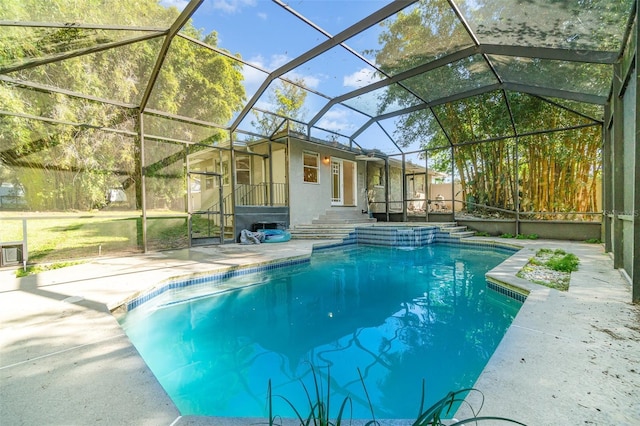 view of pool with a patio area, a pool with connected hot tub, and glass enclosure