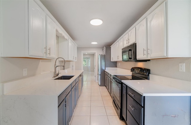 kitchen featuring light tile patterned floors, light countertops, white cabinets, a sink, and black appliances