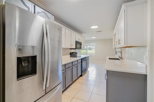 kitchen featuring light tile patterned flooring, a sink, visible vents, light countertops, and black appliances