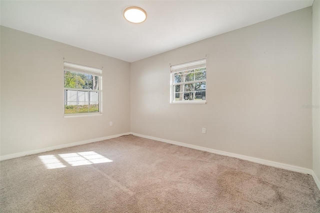 carpeted spare room featuring plenty of natural light and baseboards