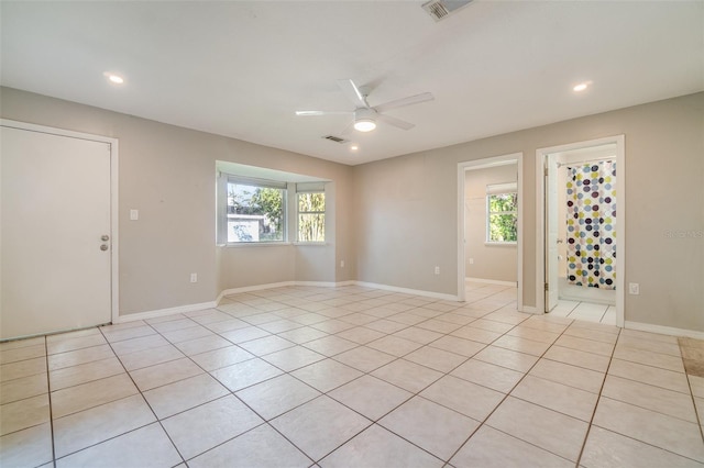 spare room with light tile patterned floors, visible vents, and a wealth of natural light