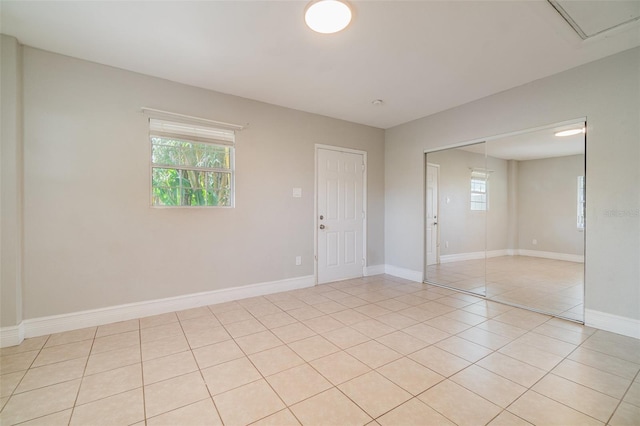 spare room featuring light tile patterned flooring and baseboards