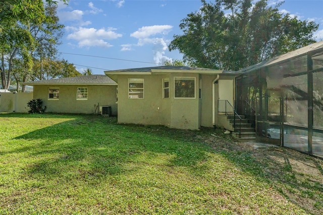 rear view of property with a lawn, fence, cooling unit, and stucco siding