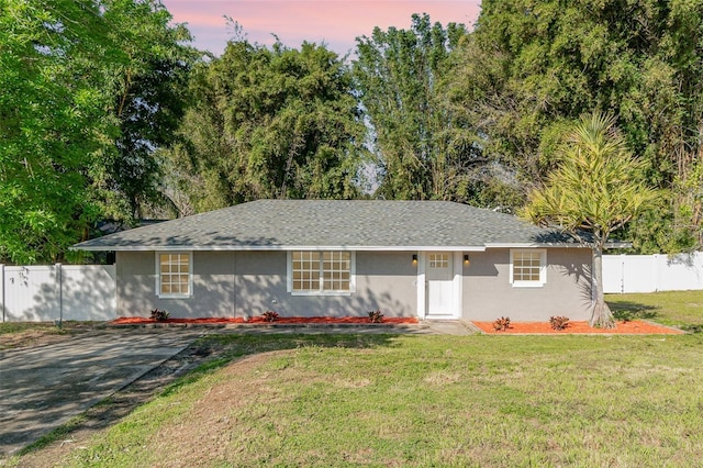 ranch-style house featuring a front yard, fence, and stucco siding