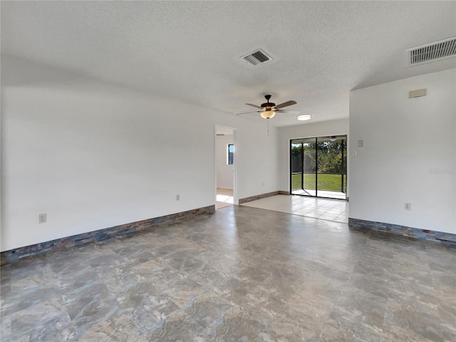 spare room with a textured ceiling, baseboards, visible vents, and a ceiling fan