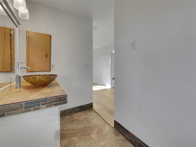 kitchen with a sink, baseboards, and light tile patterned floors