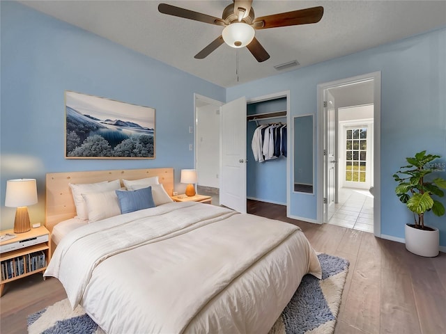 bedroom featuring a closet, visible vents, a ceiling fan, wood finished floors, and baseboards