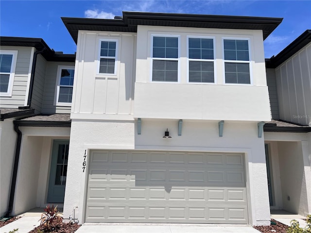 exterior space with board and batten siding, an attached garage, and stucco siding