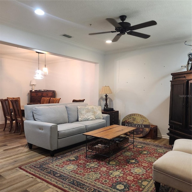 living area featuring crown molding, light wood-style floors, and visible vents