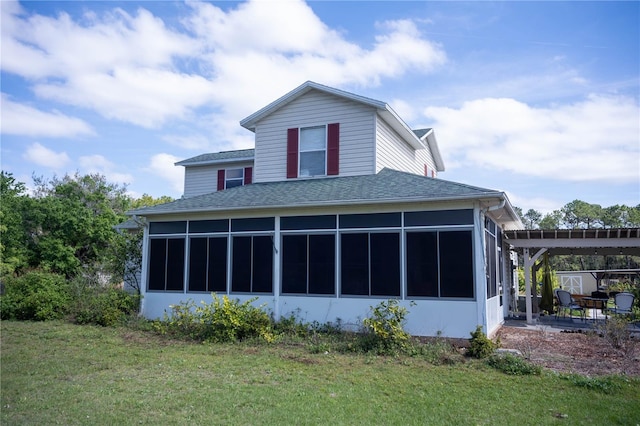 back of house with a yard, roof with shingles, and a sunroom