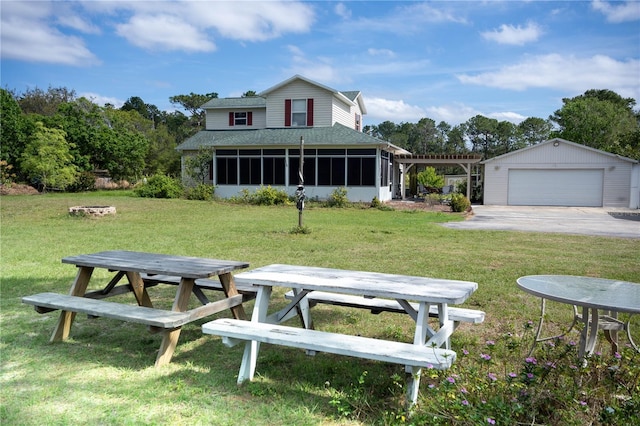 view of front facade featuring a shingled roof, a sunroom, an outbuilding, a front lawn, and a pergola