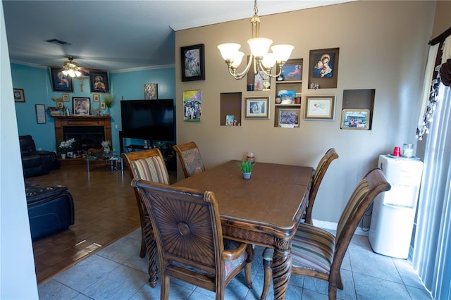 dining space featuring tile patterned flooring, visible vents, crown molding, and ceiling fan with notable chandelier