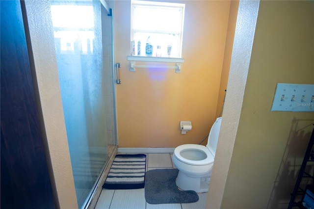 bathroom with baseboards, tile patterned flooring, toilet, and a shower stall