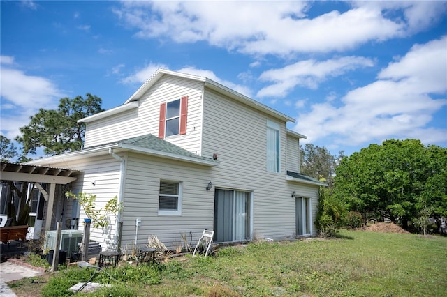 back of house with cooling unit and a lawn