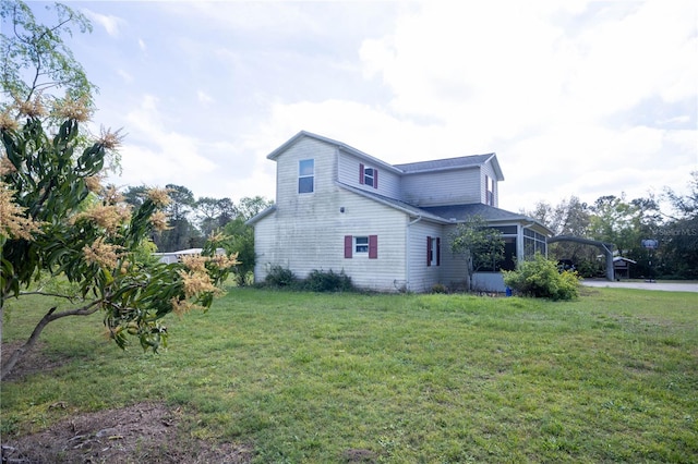 view of property exterior with a sunroom, an attached carport, and a lawn