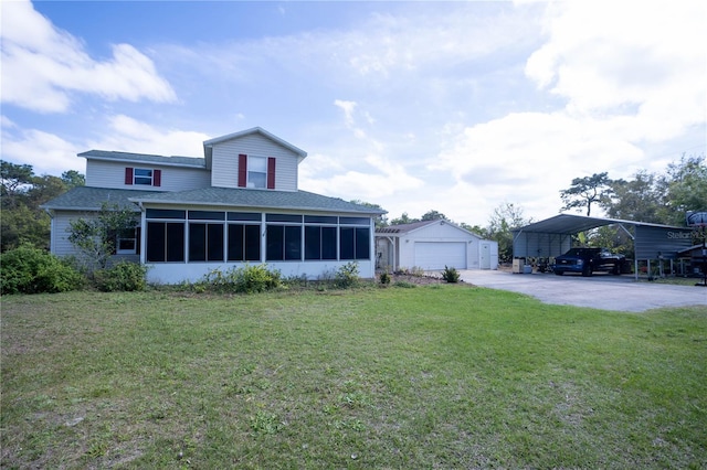 exterior space featuring driveway, a sunroom, an outbuilding, and a yard