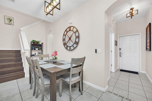 dining space with arched walkways, light tile patterned flooring, a chandelier, baseboards, and stairs