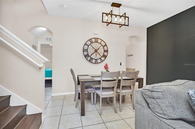 dining space featuring arched walkways, visible vents, light tile patterned flooring, a chandelier, and stairs