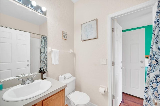 full bath featuring toilet, wood finished floors, and vanity