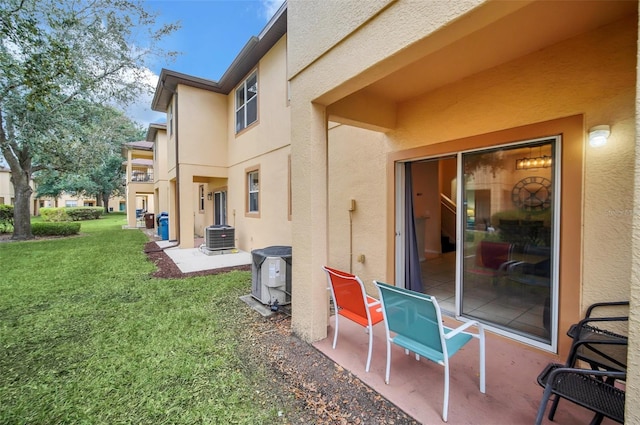 rear view of house featuring central AC, a lawn, a patio, and stucco siding