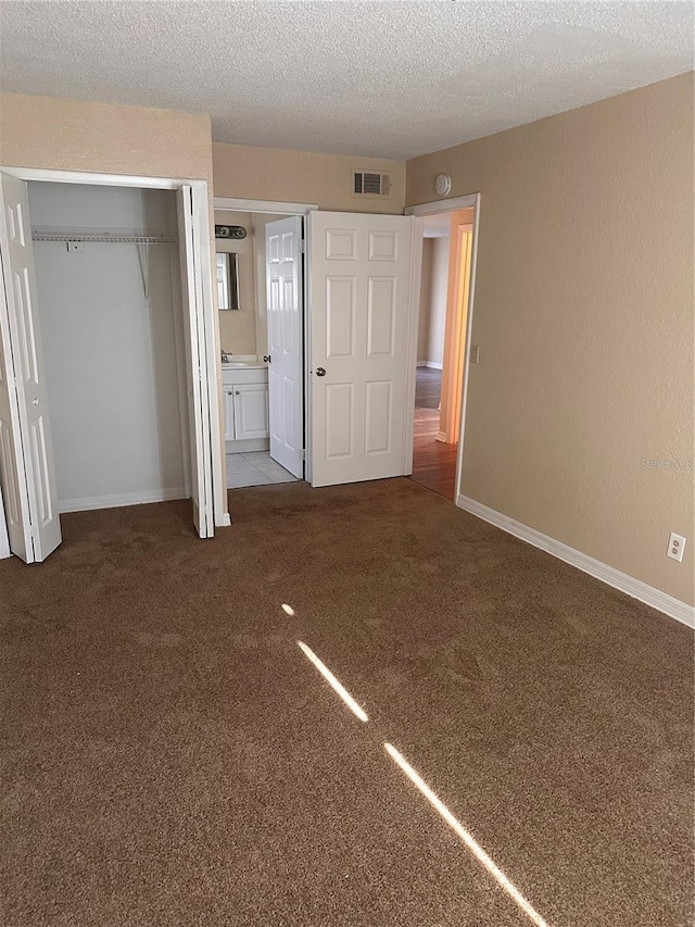 unfurnished bedroom with visible vents, baseboards, carpet floors, a closet, and a textured ceiling