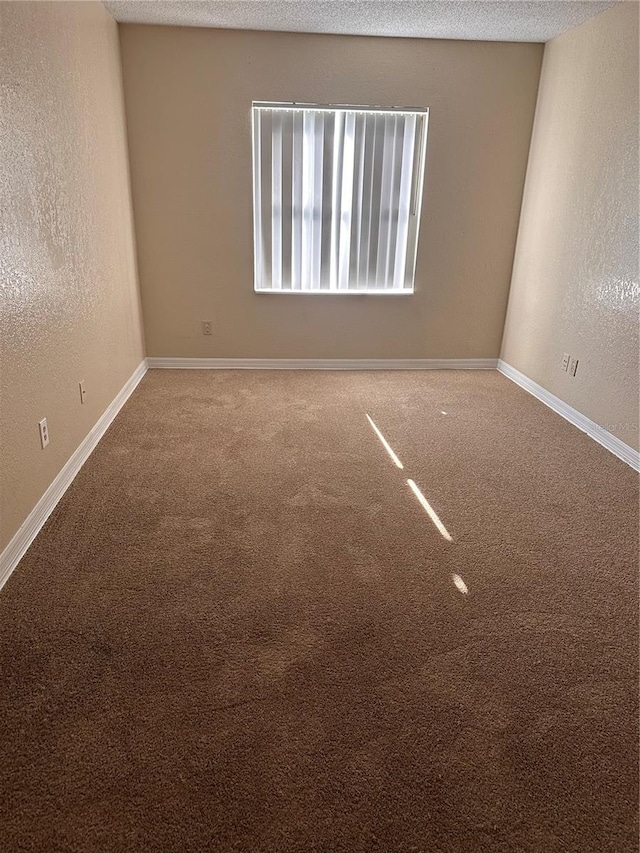 unfurnished room with a textured ceiling, baseboards, and a textured wall