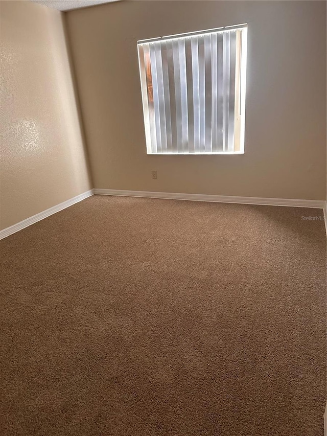 carpeted spare room with baseboards