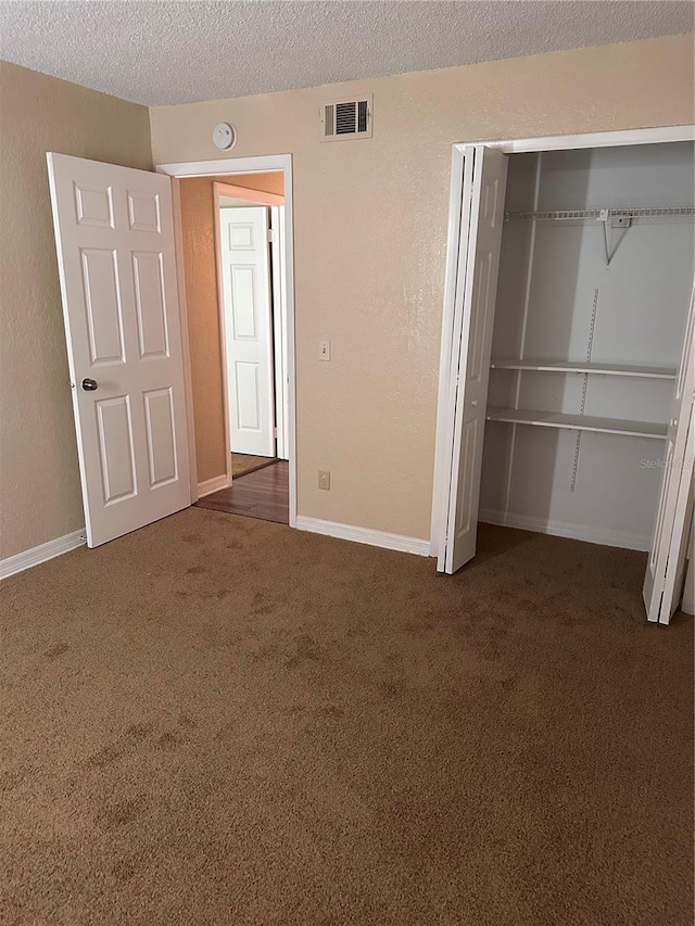 unfurnished bedroom featuring visible vents, baseboards, carpet, a closet, and a textured ceiling