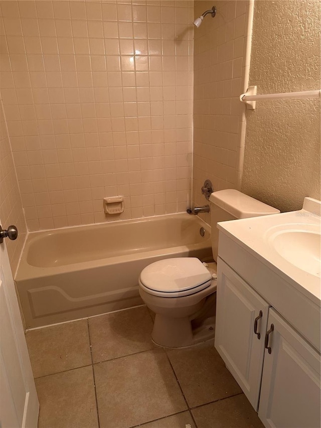 full bath featuring shower / tub combination, tile patterned floors, toilet, and a textured wall