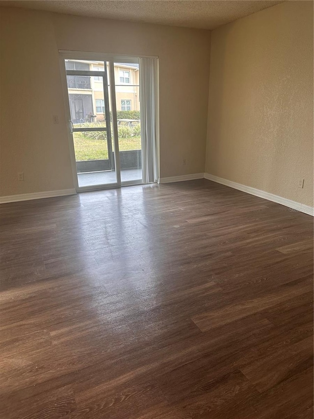 unfurnished room featuring baseboards, a textured ceiling, and dark wood-style floors