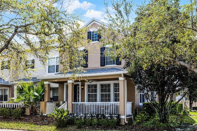 traditional-style house with covered porch, metal roof, stucco siding, and a standing seam roof